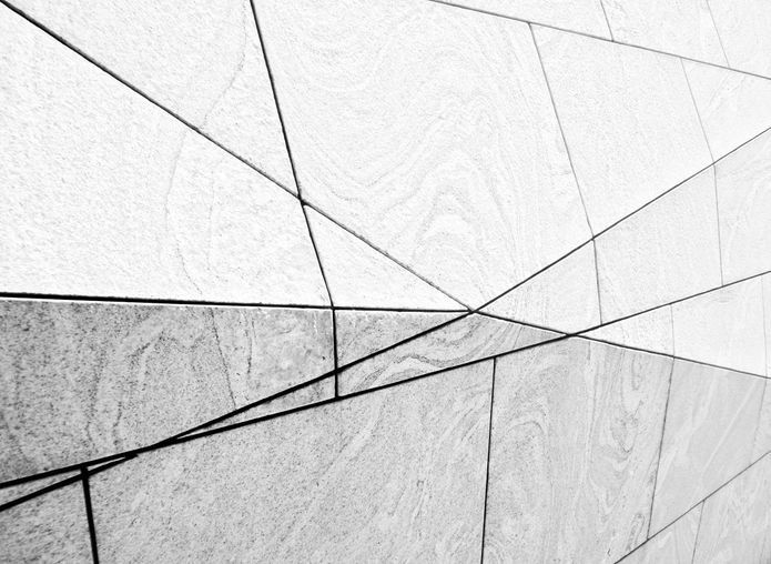Black-and-white photograph of a minimalist modern façade with geometric lines and contrasting surfaces